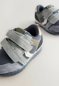 Marineblå og grå sneakers med velcro-remme, mesh-textur, gummisåler og diskrete farveaccenter. Har en forstærket tå og polstret tunge.