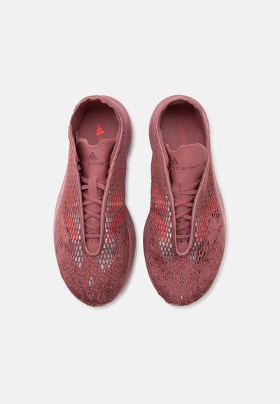 Ζευγάρι ροζ sneakers από δαντέλα και διαπνέον ύφασμα με κορδόνια και επωνυμίες στα πέλματα, προβολή από πάνω σε λευκό φόντο.