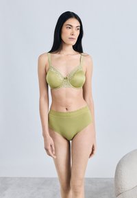 Zielony biustonosz z koronkową lamówką i kokardką, w komplecie z wysokim stanem dopasowanych majtek z teksturowanym pasem. Gładkie wykończenie materiału.