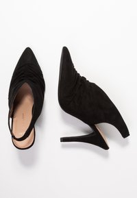 Scarpe con tacco alto in suede nero, con punta affusolata, schienale aperto e design arricciato sulla parte superiore, dotate di un sottile tacco a stiletto.