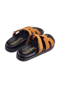 Infradito in suede marrone con tre fasce larghe, dotate di borchie metalliche e una suola in gomma nera, etichettate "Yokono Made in Spain."