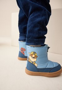 Blaue wasserdichte Stiefel mit einem strukturierten Design, versehen mit Cartoon-Figuren an den Seiten, braunen Gummisohlen und einem gepolsterten Knöchelbereich für Komfort.