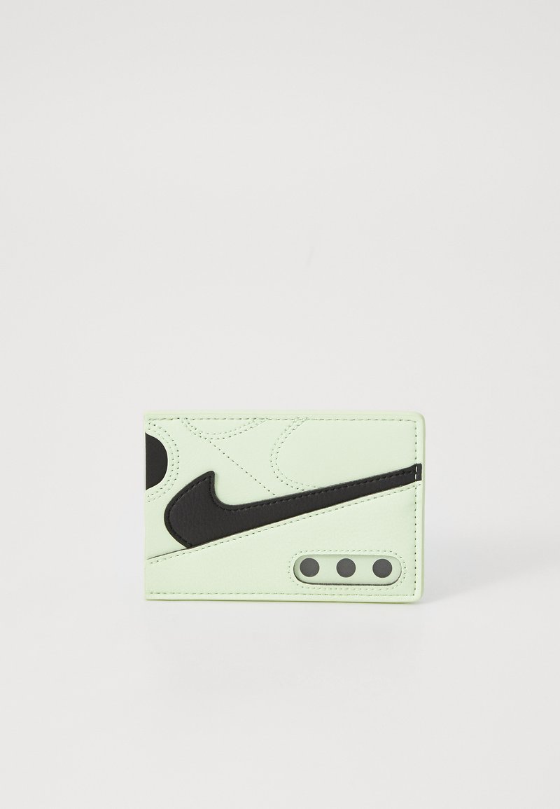 Green leather wallet featuring a large black Nike logo, textured design, and three circular cutouts at the bottom right.