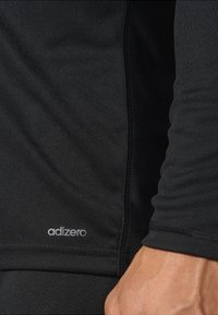 T-shirt de sport noir à manches longues, avec une texture lisse et des coutures contrastées. Le logo "adizero" est visible près de l'ourlet.