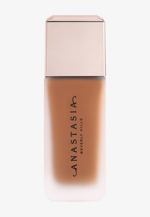 Flacon de fond de teint mat en verre dépoli avec un bouchon beige, étiqueté "Anastasia Beverly Hills" en texte vertical noir.