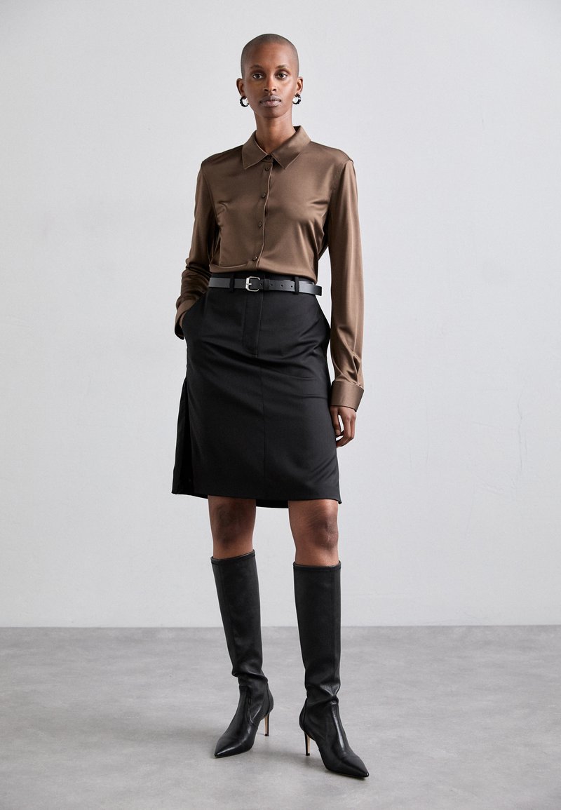 Brown satin collared shirt, black belted skirt with pockets, knee-high black leather boots. Smooth texture, structured design.