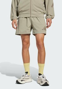 Lysgrå atletiske shorts med sidelommer og et subtilt mønster. Sammen med gule sokker og elegante sort-hvide sneakers.