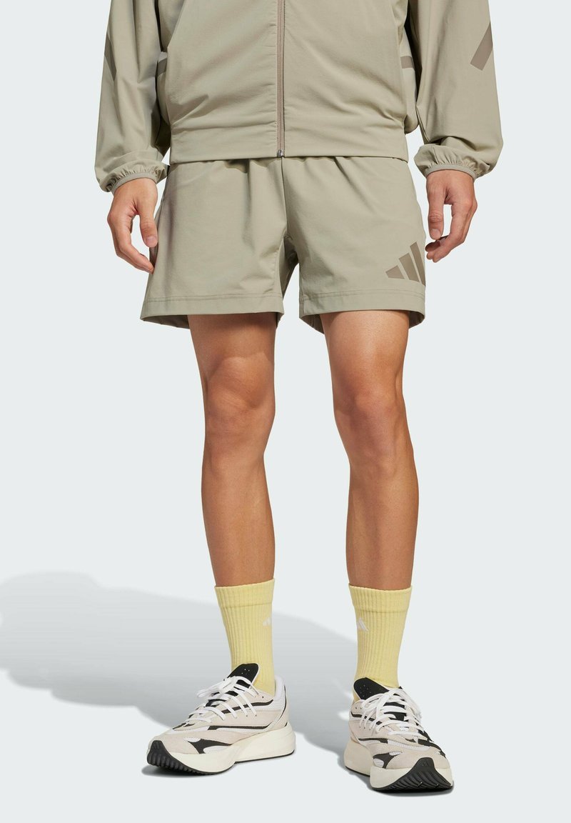 Lysgrå atletiske shorts med sidelommer og et subtilt mønster. Sammen med gule sokker og elegante sort-hvide sneakers.