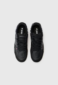 Black sneakers with a textured leather and synthetic upper, featuring a padded neckline, black laces, and contrasting logo details.