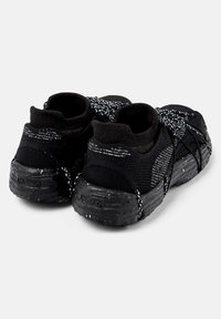 Svarta träningssneakers har en texturerad nätöverkonstruktion, elastiska snören och en gummisul med ett prickigt mönster.