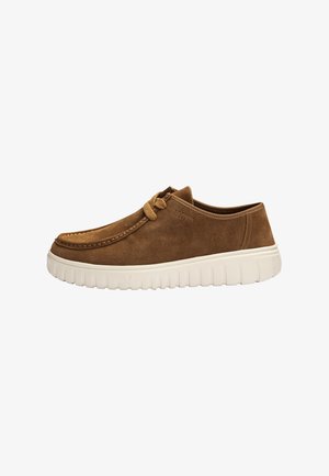 Bruine suède casual schoen met beige dikke rubberen zool en veterdetail aan de bovenkant, zijaanzicht op witte achtergrond.