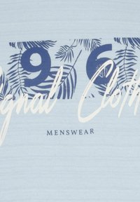 Šviesiai mėlynas marškinėlis su tamsiai mėlynomis grafikos detalėmis, palmės lapų dizainu, užrašu "196" ir "Original Clothing" baltu šriftu. Žemiau esantis užrašas "Menswear".