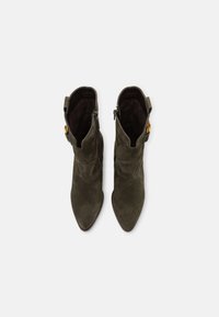 Stivaletti in suede verde con punta affusolata e dettagli decorativi sui lati. Presentano cerniere e una morbida foderatura in tessuto.