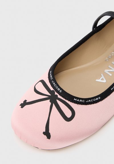 Ružičasta ravna cipela s grafikom crne mašne, elastičnim crnim rubom oko otvora i glatkom površinskom teksturom, označena sa "Marc Jacobs."