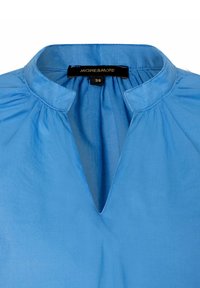 Himmelblaue Bluse mit Stehkragen, V-Ausschnitt und sanften Falten an der Halslinie. Hergestellt aus glattem Stoff. Größe 36.