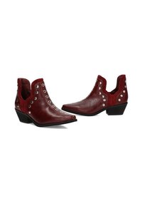 Botines de cuero rojo hasta el tobillo con lados recortados, tachuelas plateadas a lo largo de la parte superior y un tacón bajo apilado. Textura lisa con un diseño de punta afilada.