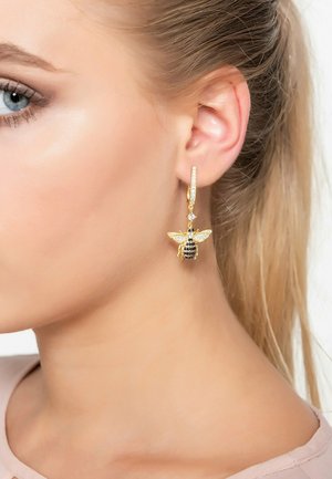 Gold earrings with a bee design, featuring black and gold accents. Sparkling details and a hoop attachment. Elegant and playful look.