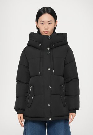 Zwarte donsjack met een hoge capuchon, vooraan drukknopen/sluitingen, ritssluitingen aan de zijkanten en een doorgestikte textuur. Groot, gewatteerd ontwerp.