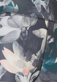 Blommönstrad tyg i nyanser av grått, blått och rosa, med en slät textur och kontrasterande svart trim längs sömmarna.