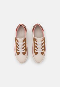 Zapatillas de deporte rosa claro y marrón con parte superior de cuero suave, acentos de ante, cordones blancos y diseño de puntera redondeada.