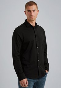 Czarna koszula z długim rękawem wykonana z bawełny, z klasycznym kołnierzykiem, zapięciem na guziki oraz dyskretnym logo na lewej piersi.