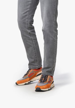 Orange and gray athletic shoes with mixed materials, featuring a textured upper, prominent lacing, and a thick, wedge-style sole.