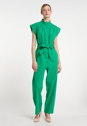 Grøn bomulds-jumpsuit med korte ærmer, en stående krave og en bælte i taljen. Løs pasform med indsnævrede ben og ingen synlige mønstre eller detaljer.
