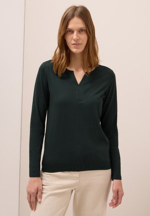 Haut à manches longues de couleur vert foncé, avec un décolleté en V et un détail cousu. Fabriqué dans un tissu lisse, il présente une coupe décontractée et un ourlet droit.