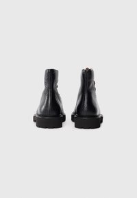 Schwarzlederne Knöchelstiefel mit strukturiertem Finish, hohem Absatz und markantem Profilsohle. Außerdem verfügen sie über eine kleine Schlaufe an der Hinterseite für einfaches Anziehen.