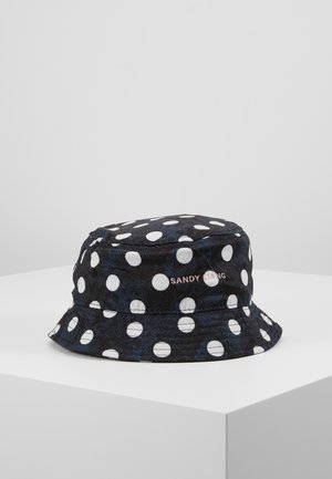 Schwarzer Bucket Hat mit weißen Punkten und "SANDY LIANG" in kleinen rosa Buchstaben auf der Seite gestickt, auf einer weißen Oberfläche präsentiert.