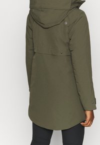 Olijfgroene, middel-lange jas met een capuchon, met een gladde textuur, drukknoopsluitingen en een afgeronde zoom. Minimalistische branding op de achterkant.