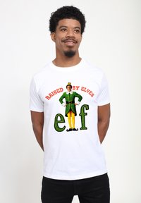 Biała koszulka z bawełny z graficznym wzorem i napisem "Wychowany przez Elfy" oraz postacią elfa w zielonych i żółtych ubraniach.