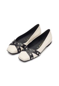 Ballerine in pelle bianca sporca con una fascetta nera borchiata sulla punta, forma a punta quadrata e suola piatta.