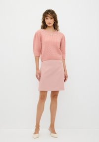 Un pull en tricot rose avec des manches bouffantes courtes, mettant en valeur des embellissements floraux au niveau de l'encolure. Associé à une jupe ajustée rose assortie.