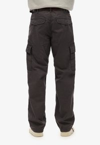 Donkergrijze cargobroek met een relaxte pasvorm, meerdere zijzakken en versterkte stiksels. Het materiaal lijkt een stevige katoenmix te zijn.
