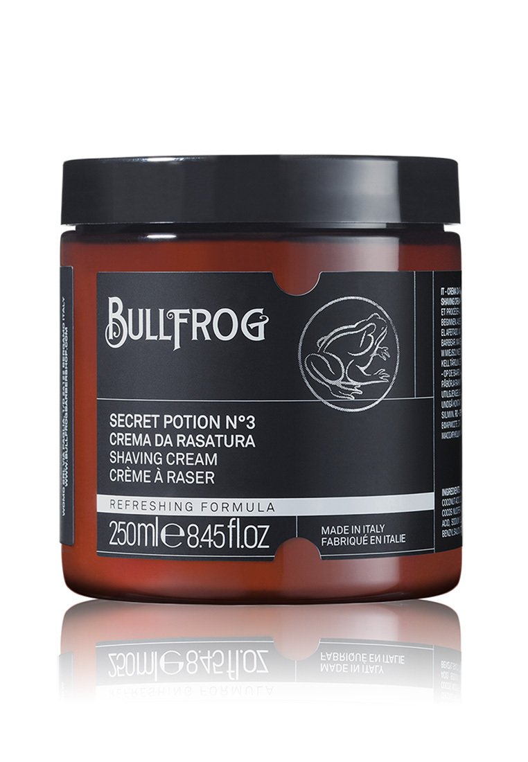 Braunes Glasgefäß mit schwarzem Deckel. Das Etikett zeigt weißen Text und eine Illustration eines Frosches. Enthält 250ml erfrischender Rasiercreme.