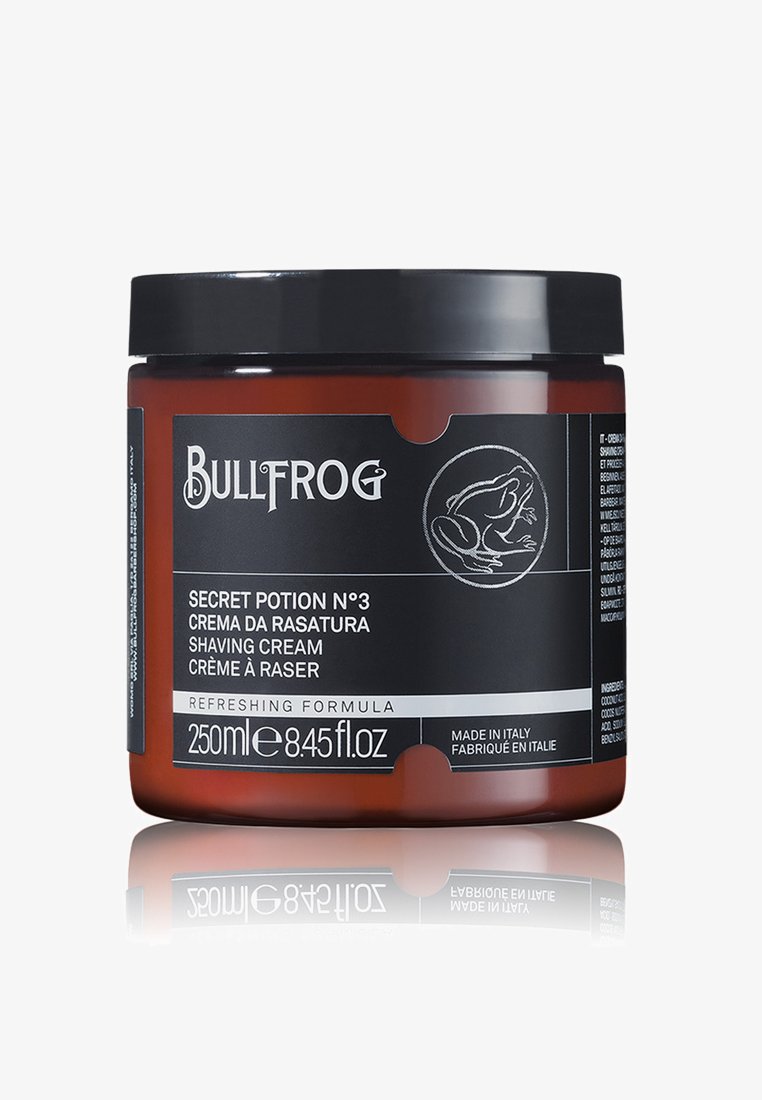 Braunes Glasgefäß mit schwarzem Deckel. Das Etikett zeigt weißen Text und eine Illustration eines Frosches. Enthält 250ml erfrischender Rasiercreme.