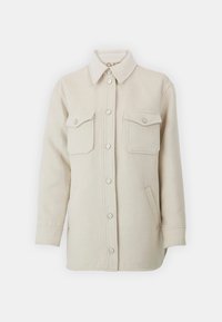 Chaqueta de camisa de forro polar en color beige claro con cuello puntiagudo, dos bolsillos en el pecho con botón y botones de presión plateados en la parte delantera.