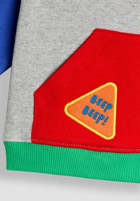 Grauer Kapuzenpullover mit blauen Ärmeln, roter Tasche mit einem orangefarbenen Dreiecksaufnäher und blauer "BEEP BEEP!"-Aufschrift sowie grünem geripptem Saum.