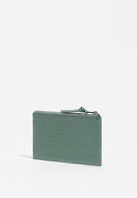Portafoglio in pelle verde con effetto coccodrillo, con chiusura a zip, forma rettangolare, texture liscia e un tirazip decorativo.