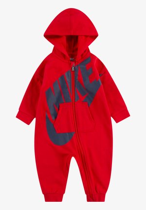 Crvena zip-up kombinezon s kapuljačom, s velikim tamnosivim Nike logotipom na prednjoj strani i kenguruvim džepom. Izrađen od mekanog materijala.