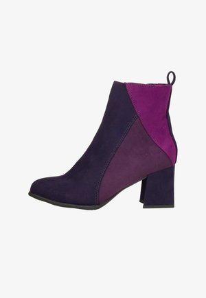 Purple and violet ankle boot with a textured suede finish, a square toe, and a chunky heel. Features a color-block design with contrasting panels.