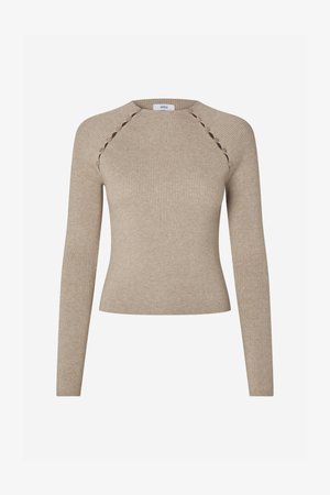 Bež dolg plašč z rebrastim vzorcem, ki ima oprijeto obliko in okrasne izreze vzdolž ramenih.}}