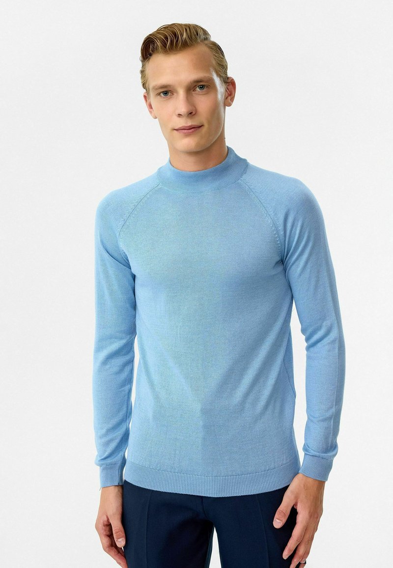 Lichtblauwe getailleerde trui met hoge hals, lange mouwen en geribbelde manchetten, gemaakt van zacht gebreid materiaal met een gladde textuur.