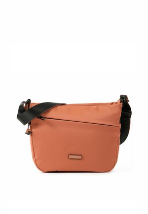 Sac bandoulière couleur rouille avec sangle noire réglable, poche zippée diagonale à l'avant et petite étiquette de marque au centre avant.