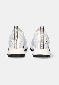 Zapatillas deportivas blancas con una parte superior de malla texturizada, decoradas con rhinestones, suelas negras y una tira de agarre trasera con texto de logo.