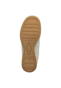 Zapatilla con suela de goma y parte superior texturizada en color crema, que presenta una suela de goma marrón, surcos marcados y un detalle de logo central en la suela exterior.