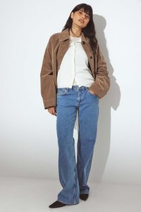 Brūna zamša jaka, balta krekls ar pogām un gaiši zili platā apakšdaļa džinsi, ar melnām norādītām kurpēm. Vienkāršs, tīrs dizains un brīvs piegriezums.