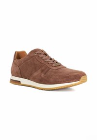 Brown suede sneaker with a textured finish, white midsole, and brown rubber outsole. Features laces and a small brand logo on the side.