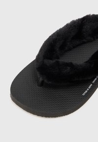 Mustad mustikad, millel on tekstureeritud kummitald ja pehme rihm, pakkudes mugavat tunnet, seljal on selge logo, mis on trükitud jalaosale.